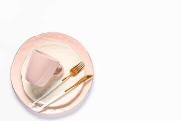 Beautiful table setting with golden cutlery and pink cup on grey background