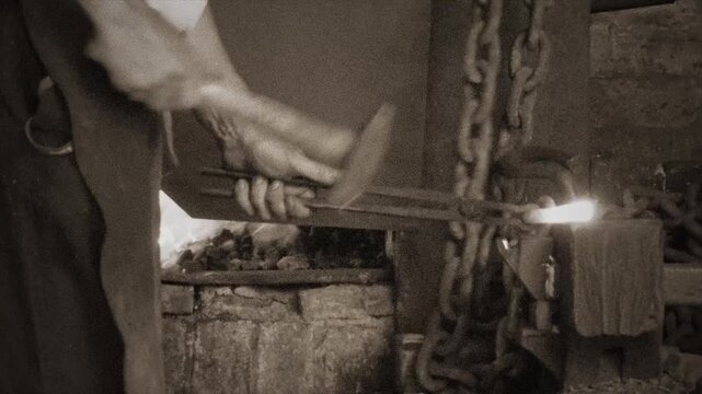 Vintage Blacksmith Forging Hot Iron Chain Links in Workshop.
Sepia-toned footage of a traditional blacksmith hammering heated iron to forge a chain link.