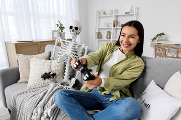 Young woman with human skeleton playing video game at home