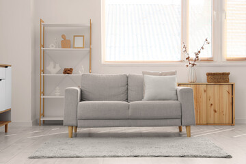 Interior of light living room with cotton flowers in vase and sofa