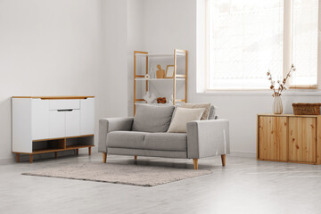 Interior of light living room with cotton flowers in vase and sofa