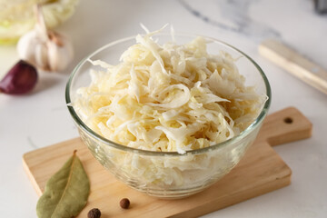 Glass bowl with tasty sauerkraut and different spices on white background, closeup