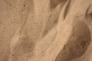Detailed close-up of natural sand grains. Fine textures and earthy tones in sunlight, perfect for backgrounds, design, and nature projects