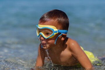 Child explores the water while wearing goggles at a sunny beach during summer