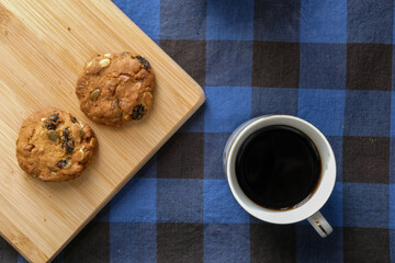 Black Coffee with Homemade Cookies on Wooden Board over Blue Plaid