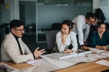 A group of business employees engaged in a collaborative brainstorming session, focusing on strategy and project analysis at a modern office environment. Teamwork and communication are emphasized.