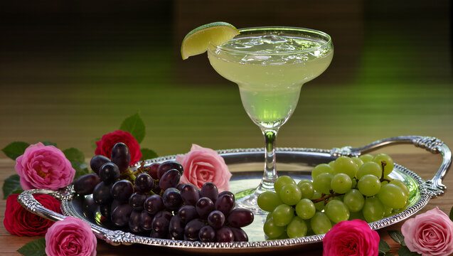 Refreshing cocktail with grapes and roses on a silver tray