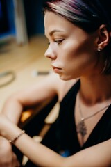 Close-up side profile of a young woman. Soft light highlights her facial features, emphasizing delicate contours and natural beauty.