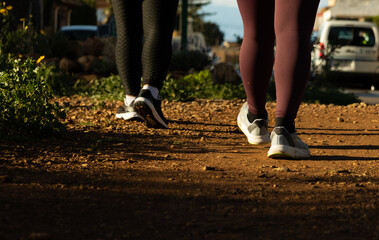 Obraz premium Close up of people’s feet walking on a dry dirt and rocky trail on a sunny day, concept of adventure, hiking, nature, and active outdoor lifestyle