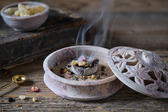 Incense and herbs burning in a traditional soapstone bowl, close-up