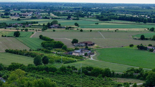 Po Valley landscape showing cultivated fields of different colors and farmhouses with Cremona skyline in background near Castelvetro Piacentino, Italy