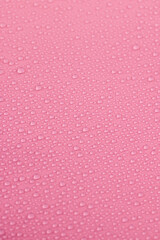 a smooth pale pink surface covered with water droplets, a beautiful wet pink film in a large number of water droplets, close up