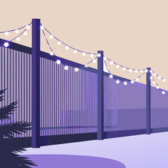 Holiday lights on fence. Decorative fence with string lights in purple evening setting  