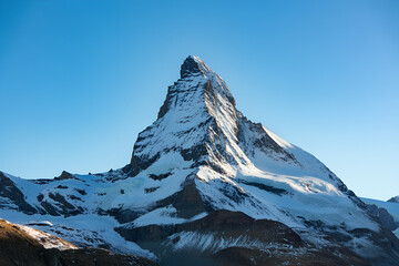 Snow Covered Rocky Mountain Landscape in Winter,Snowy mountain peak in winter,Scenic aerial view of snow,Matterhorn Mountain Peak in Winter with Snow & Clear Blue Sky,Minimalist snowy mountain peak,Ai