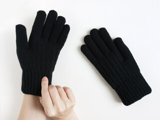 Caucasian woman trying on black winter fur gloves on her hands. White background. Top view.