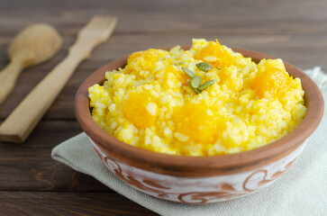 Pumpkin risotto in a ceramic bowl on a brown wooden table. Italian food concept. Rustic style. Autumn food. Selective focus. Horizontal orientation. Copy space.