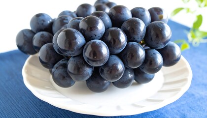 A bunch of dark purple grapes on a white plate