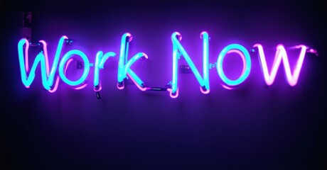 Bright neon sign displays Work Now. Vivid purple, turquoise glow against dark background. Simple message, motivational vibe.