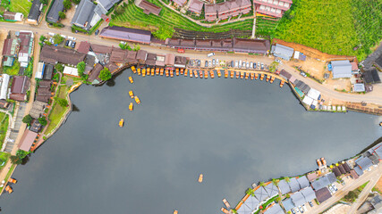 aerial top view of a lakeside village, showcasing a mix of rustic architecture, lush greenery, and...
