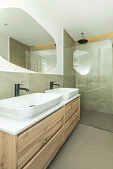 Modern bathroom with double porcelain sinks on a floating vanity unit, low-profile chrome faucets, and a tempered glass corner shower enclosure