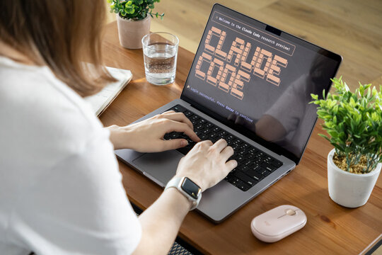 Poznan, Poland - August 23, 2025: Woman actively typing on her laptop, screen displaying Claude Code research preview for software development and programming innovation