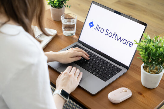 Poznan, Poland - August 23, 2025: Jira Software application displayed on laptop screen, woman typing, emphasizing project management, task tracking, and team efficiency