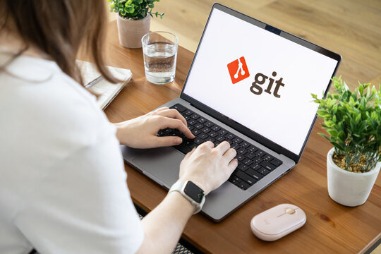 Poznan, Poland - August 23, 2025: Git application logo on a laptop screen, showing a person typing, emphasizing collaborative software development and version control