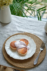 Syrniki with pink cream on a white plate. Side view. 