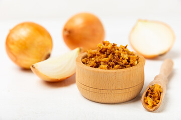 Crispy fried onions in a bowl on a wooden table. Roasted Onions. Seasoning for dishes. Spices. Salad dressing. Space for text. Copy space