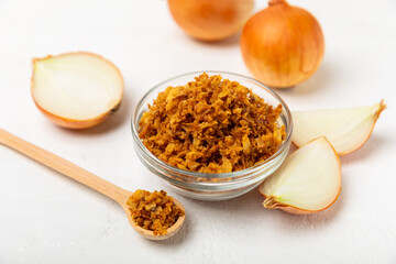 Crispy fried onions in a bowl on a wooden table. Roasted Onions. Seasoning for dishes. Spices. Salad dressing. Space for text. Copy space