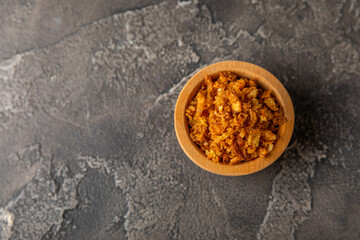 Crispy fried onions in a bowl on a wooden table. Roasted Onions. Seasoning for dishes. Spices. Salad dressing. Space for text. Copy space