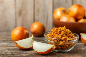 Crispy fried onions in a bowl on a wooden table. Roasted Onions. Seasoning for dishes. Spices. Salad dressing. Space for text. Copy space