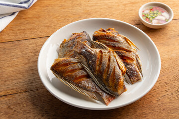 Fried Sun dried tilapia fish in a plate.with fish sauce chili and lime dipping sauce.