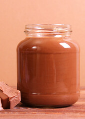 chocolate paste in a glass jar on a colored background.. Vertical photo format