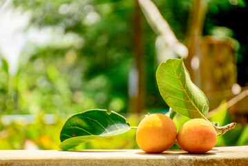 Two Ripe Orange wild fruit with Green Leaves on a Sunny Day, Wooden table surface with orange.
