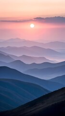 Obraz premium Soft pink sunrise over misty blue mountain ridges