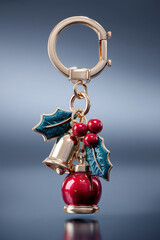 studio shot of a luxury 3d keychain with Christmas-themed charms (holly leaves, bell, snow globe), sharp details, high-end product photography lighting, clean gradient background