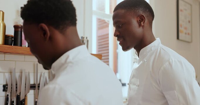 Black man, chef and discussion at kitchen, restaurant or team for planning, advice or listen for training. People, mentor and talk with learning, culinary arts and cuisine with cooking at workplace