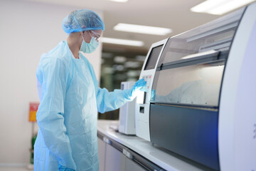 Laboratory technician operates advanced machine in clean room during research process