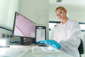 Young scientist examines slides in a modern laboratory setting with digital display