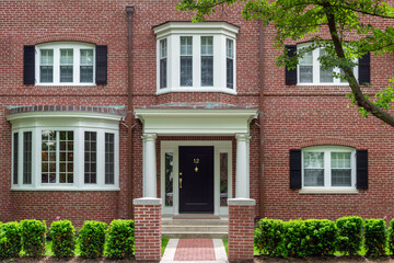 Traditional townhouse entrance with bay windows and manicured front greenery in Brookline, Massachusetts, USA
