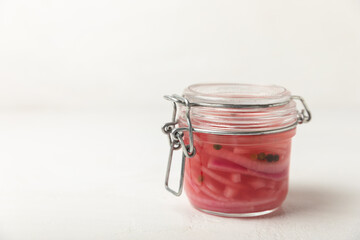 Pickled onions in a glass jar on the table. pickled red onion. Vegetarian spicy dish. Delicious homemade marinated pickled purple onions . Space for text. Copy space.