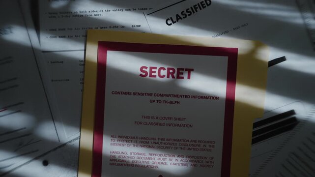 Top secret manila folder with various classified censored documents and files. Stack pile of papers with government surveillance and intelligence sensitive information. Dark room and mysterious shadow