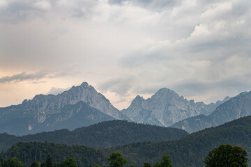 Fototapeta premium Majestic mountain range under cloudy sky near quiet valley at dusk