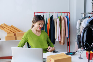 Online seller presenting clothes selling online using laptop live streaming, working at home