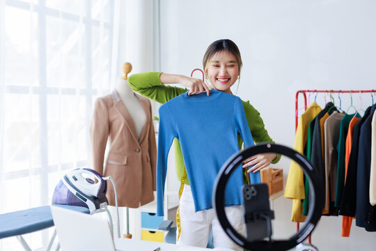 Asian fashion designer presenting clothes using smartphone and led ring light - Powered by Adobe