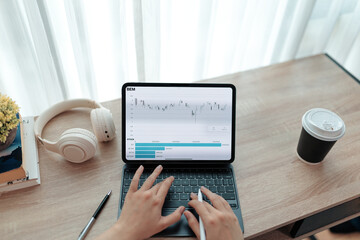 Trader analyzing stock market data on tablet with keyboard at desk