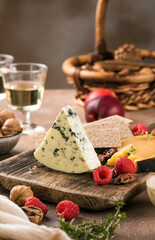 Delicious blue cheese served with fresh berries and assorted nuts on rustic wooden background.