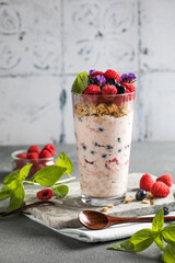 Granola with yogurt and fresh raspberries in glass on light background
