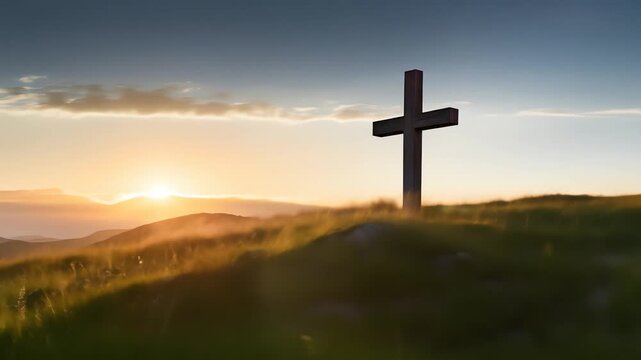 A dark cross stands on a grassy hill at sunset